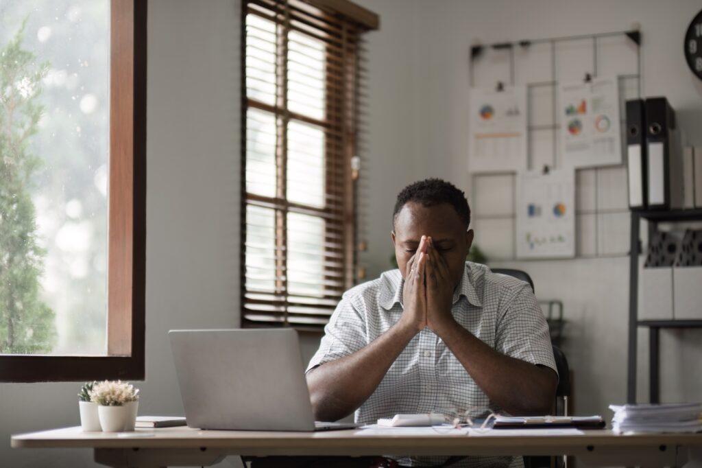 Stressed Male Office Worker Struggling with Deadlines and Workload in a Modern Office Environment